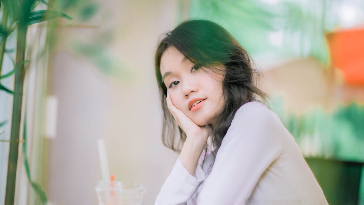 Calm indoor portrait capturing a young woman resting her head in her hand with a serene expression.